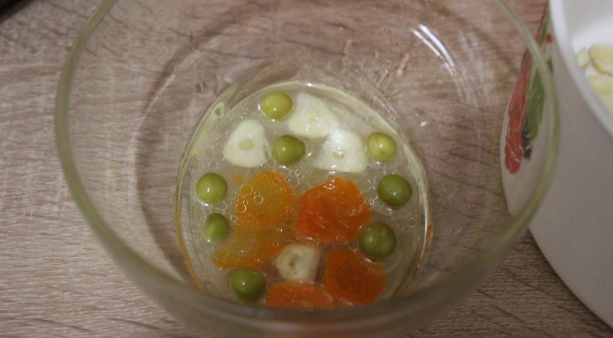 Чеснок, горошек и морковь выложить в миску, налить немного бульона