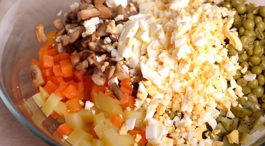 Соединяем в салатнике морковь, картофель, яйца, горошек, огурцы, грибы, соль, заправляем