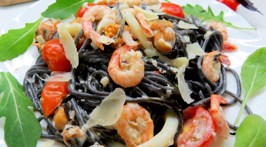 Выложить спагетти с чернилами каракатицы на тарелку, добавить сливочный соус с морепродуктами